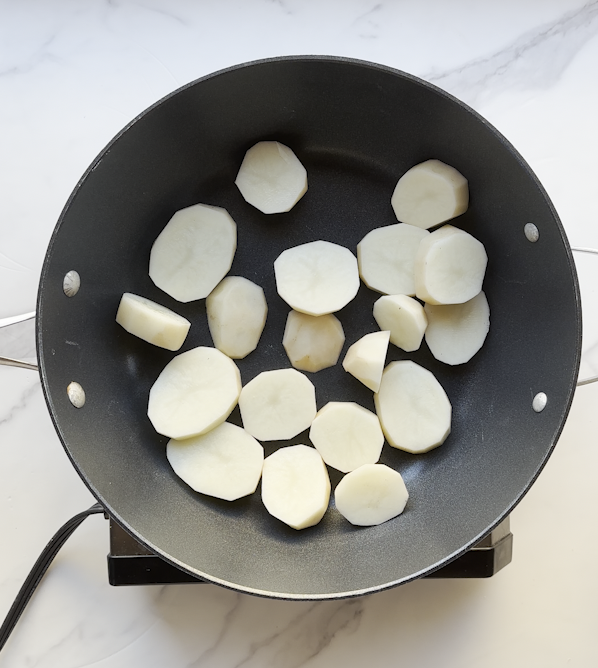 a pot full of cut up russet brand potatoes in a hockey puck style getting ready to cook